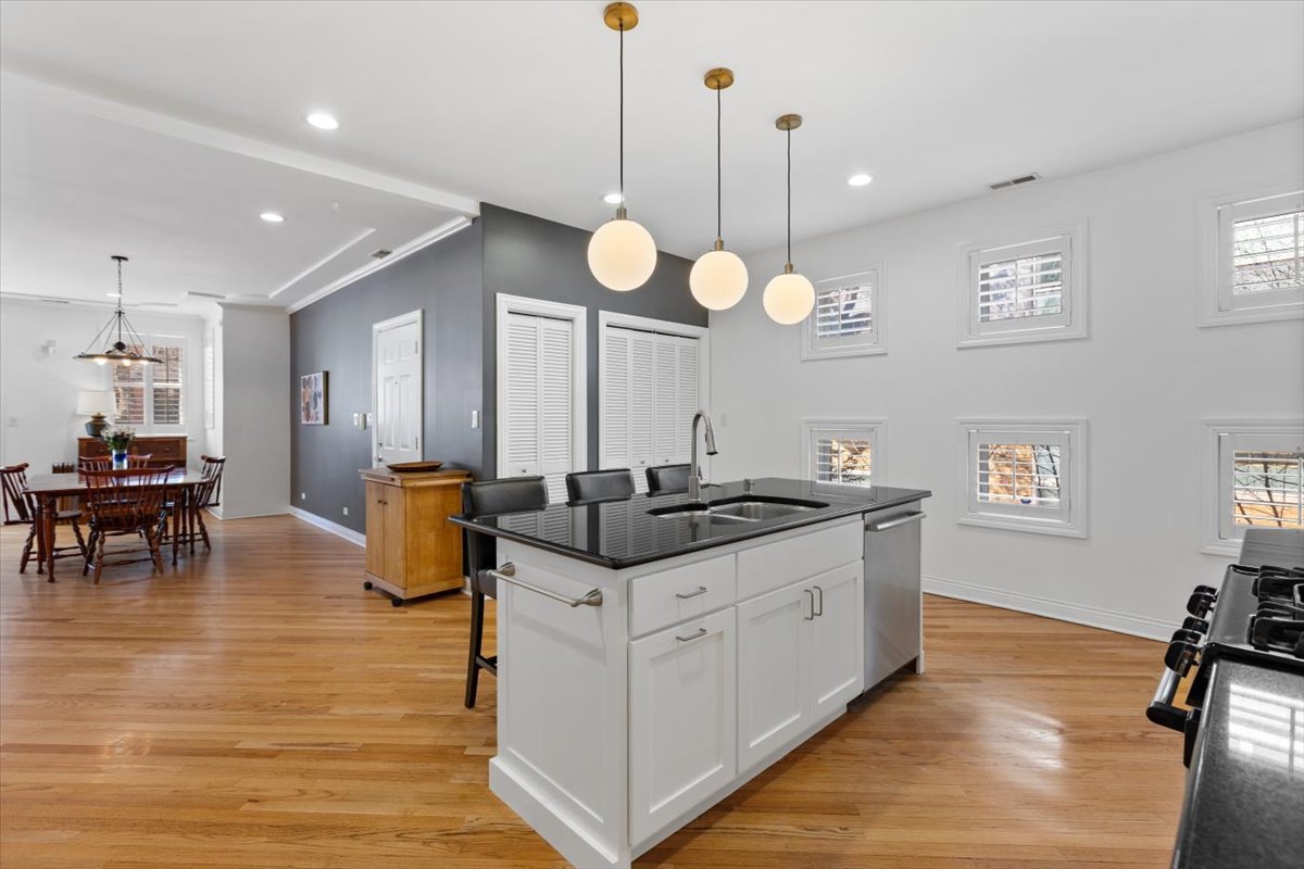 1249 North Wolcott Avenue, Unit 2 Chicago, IL 60622 - Photo 13 of 26 a kitchen with granite countertop a stove a sink a dining table and chairs with wooden floor