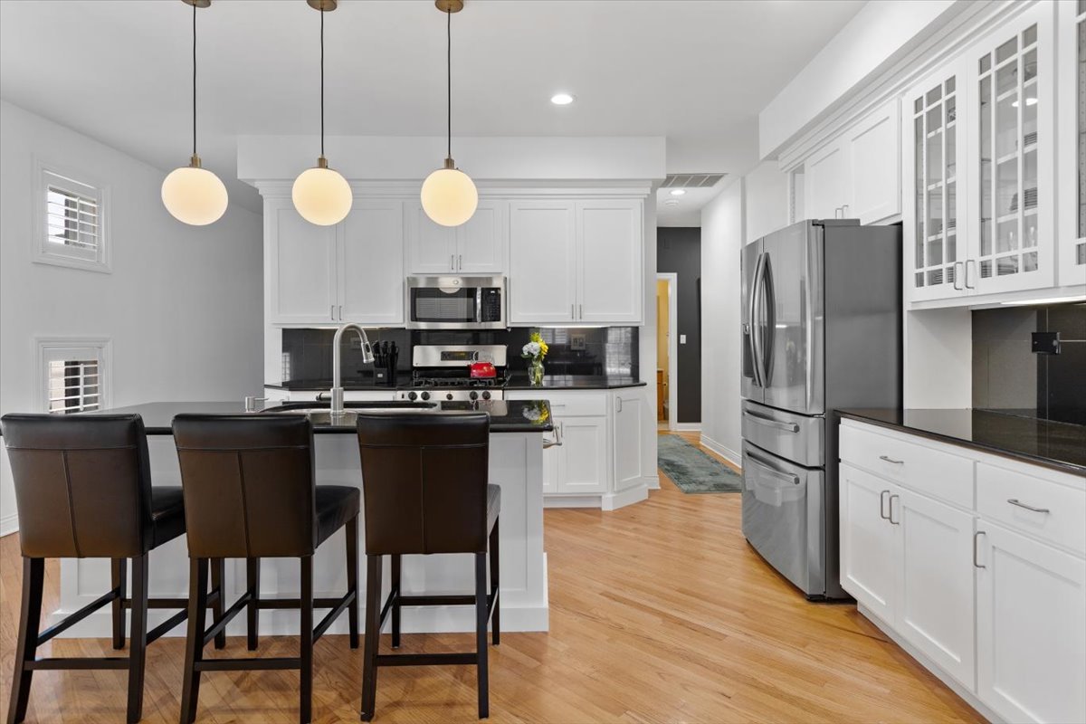 1249 North Wolcott Avenue, Unit 2 Chicago, IL 60622 - Photo 10 of 26 a kitchen with stainless steel appliances kitchen island granite countertop a refrigerator a stove a kitchen island with chairs and wooden floor