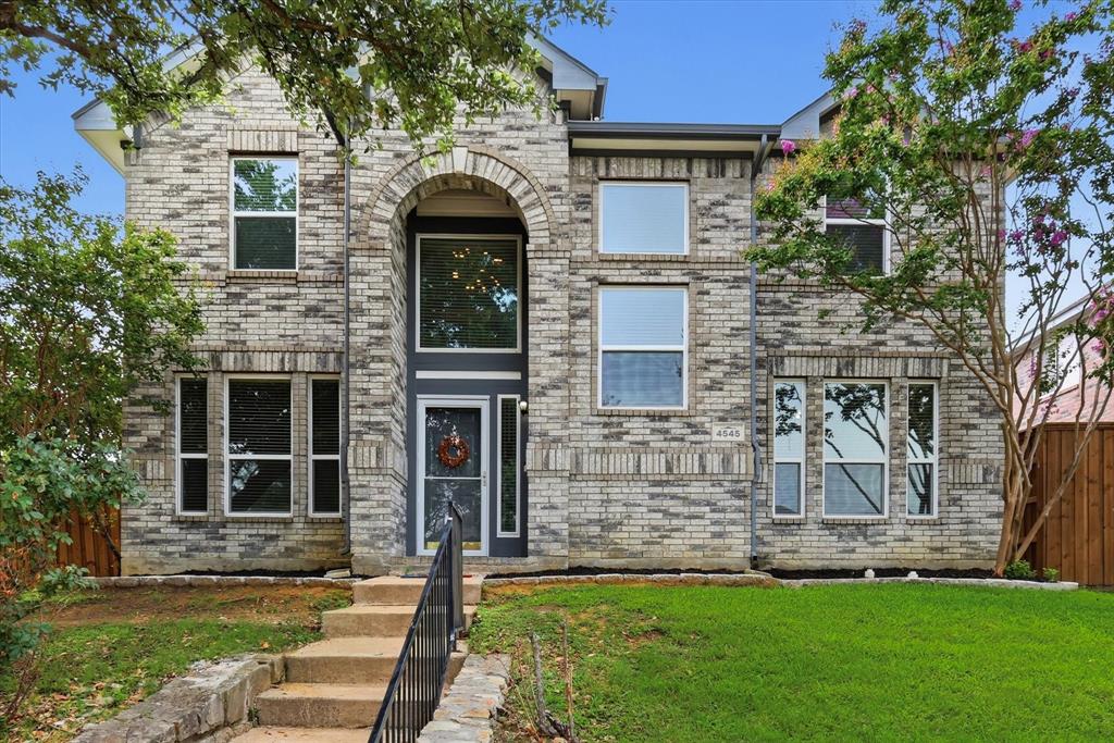 4545 Ridgepointe Drive The Colony, TX 75056 - Photo 1 of 37 Two-story brick facade featuring an arched entryway with a full-light door and sidelights, multiple large windows, and a manicured lawn