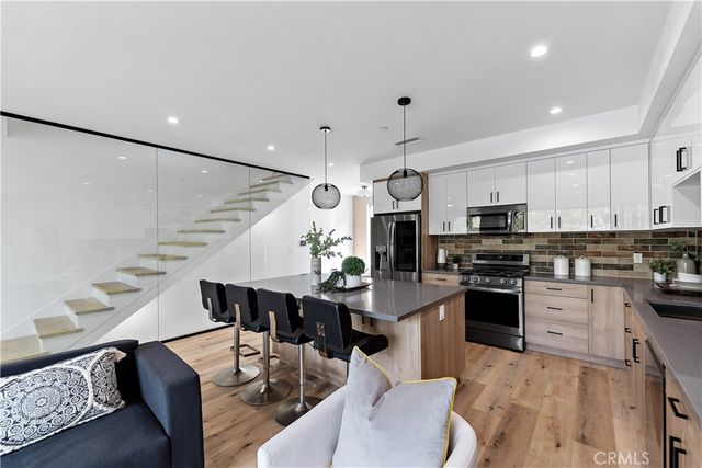 a kitchen with stainless steel appliances a sink a stove a microwave a center island and cabinets