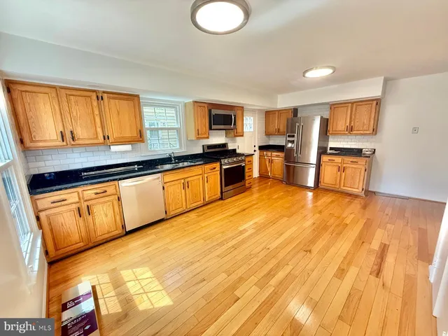 a large kitchen with stainless steel appliances granite countertop a stove top oven a sink with granite countertops and cabinets