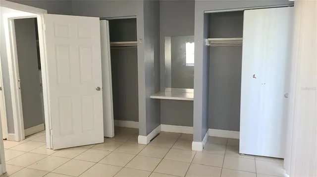 a view of an empty room with cabinet and mirrors