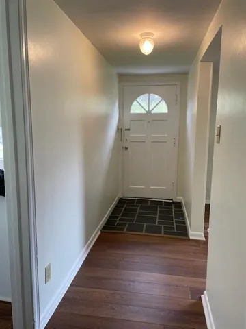 a view of a hallway with wooden floor and white walls
