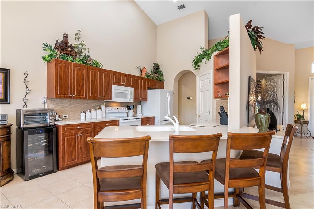 8931 Lely Island Circle Naples, FL 34113 - Photo 17 of 46 a kitchen with stainless steel appliances kitchen island granite countertop a table and chairs in it