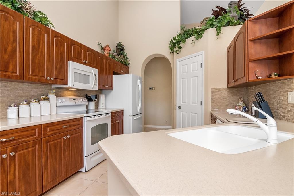8931 Lely Island Circle Naples, FL 34113 - Photo 18 of 46 a kitchen with stainless steel appliances kitchen island wooden cabinets a stove and a sink