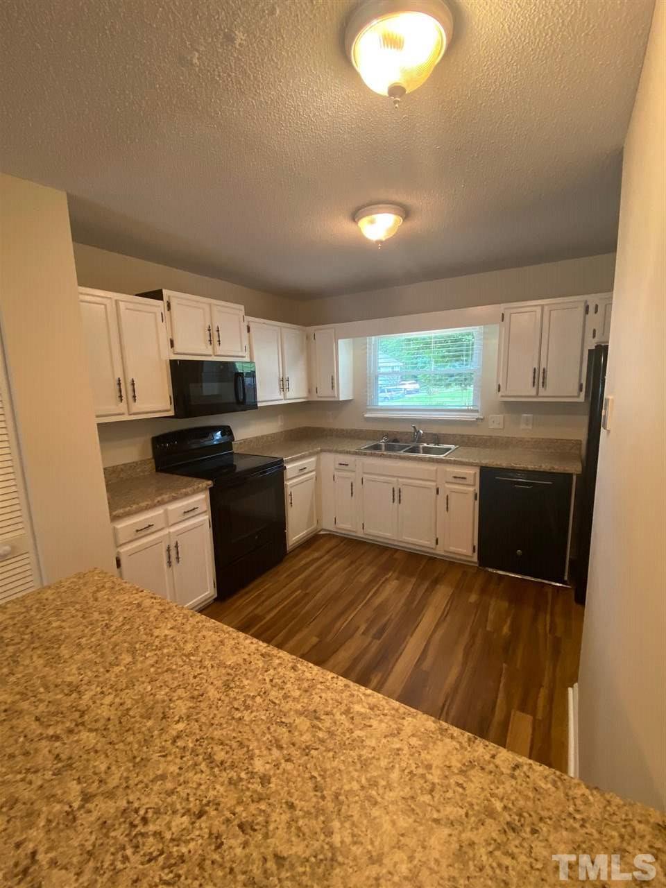 5484 Pine Top Circle Raleigh, NC 27612 - Photo 2 of 6 a kitchen with a sink a stove a microwave a counter top space and cabinets