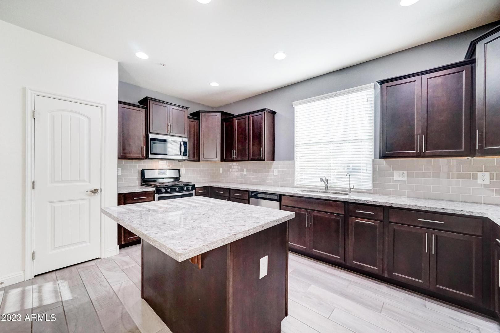 2297 North Alsap Road Buckeye, AZ 85396 - Photo 8 of 36 a kitchen with a sink stove and cabinets