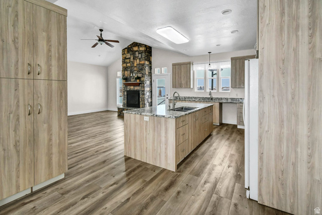 1103 North Brooklyn Road Monroe, UT 84754 - Photo 76 of 78 Kitchen with open floor plan, light stone countertops, a stone fireplace, freestanding refrigerator, and a center island with sink