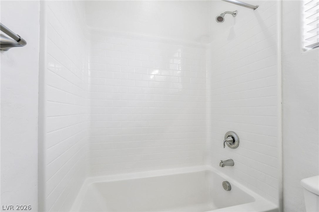 6245 Andover Wood Road Las Vegas, NV 89113 - Photo 27 of 37 A pristine white tiled shower-over-tub combination offers a clean, functional bathing space.