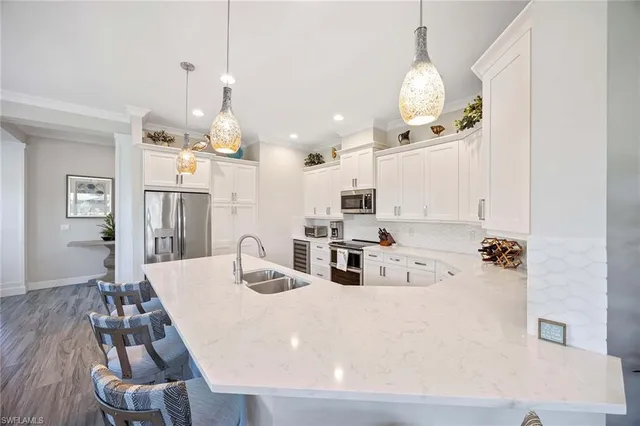 a kitchen with stainless steel appliances kitchen island granite countertop a sink a refrigerator and chairs