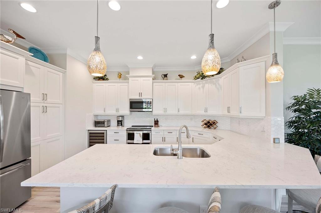 5626 Elbow Avenue Naples, FL 34113 - Photo 13 of 48 a kitchen that has a lot of cabinets and stainless steel appliances