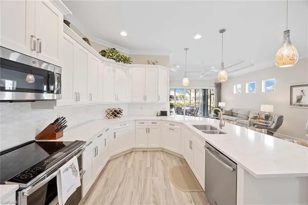 a large white kitchen with a stove a sink a refrigerator and a microwave