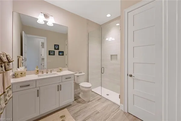 a bathroom with a double vanity sink toilet mirror and windows