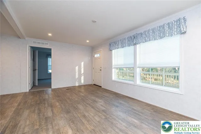 a view of an empty room with a window and wooden floor