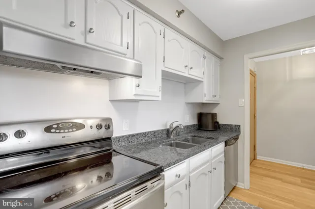 a kitchen with granite countertop stainless steel appliances a sink stove top oven and cabinets