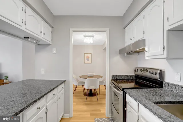 a kitchen with granite countertop a stove and a white cabinets