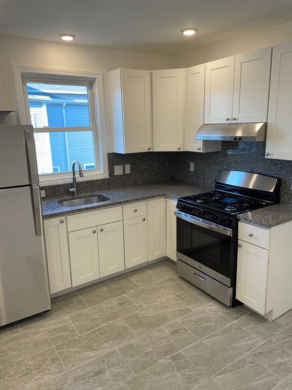 217 Washington Street, Unit 7 Lynn, MA 01902 - Photo 1 of 16 a kitchen with granite countertop white cabinets and stainless steel appliances