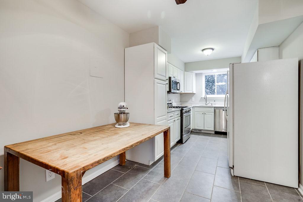 11041 Saffold Way Reston, VA 20190 - Photo 13 of 44 a kitchen with a table chairs refrigerator and cabinets