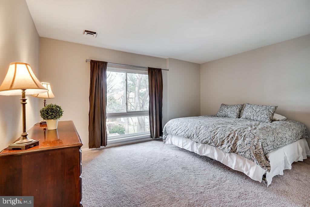 11041 Saffold Way Reston, VA 20190 - Photo 22 of 44 a spacious bedroom with a bed and a flat tv screen on dresser