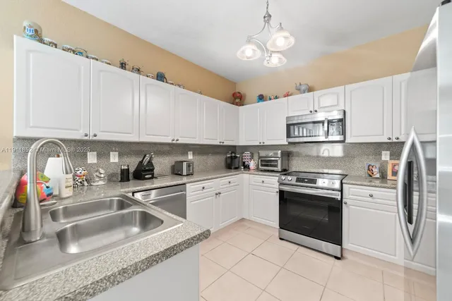 a kitchen with granite countertop a sink stainless steel appliances and white cabinets