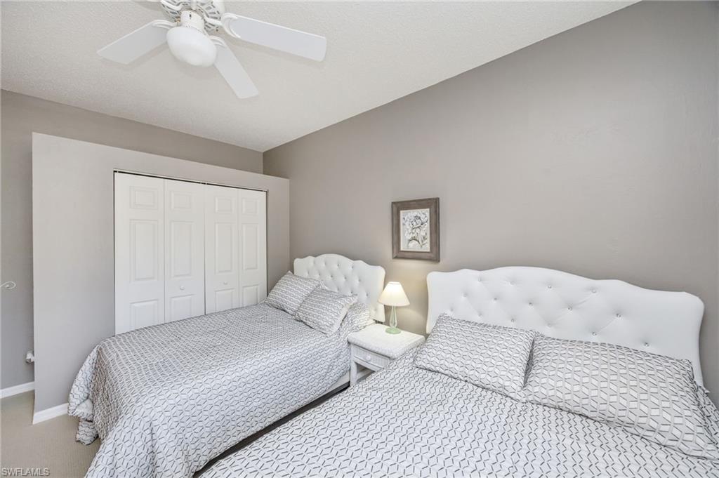 89 Silver Oaks Circle, Unit 5201 Naples, FL 34119 - Photo 18 of 21 a bedroom with a white bed and a chandelier