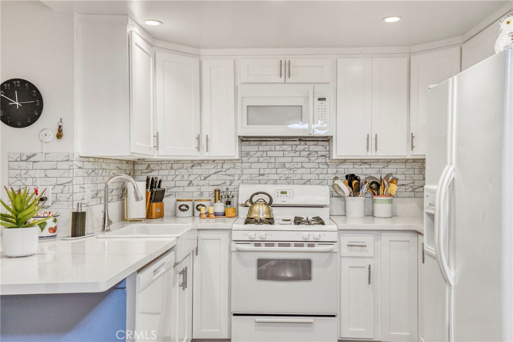 15155 Sherman Way, Unit 14 Van Nuys, CA 91405 - Photo 13 of 36 a kitchen with stainless steel appliances granite countertop a sink stove and white cabinets with wooden floor