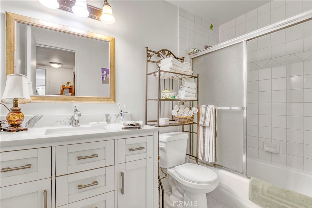 15155 Sherman Way, Unit 14 Van Nuys, CA 91405 - Photo 21 of 36 a bathroom with a granite countertop toilet sink and a mirror
