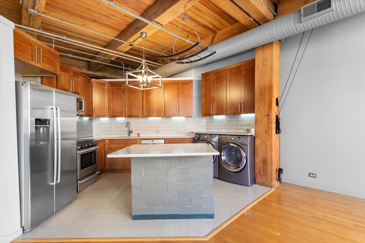 913 West Van Buren Street, Unit 4C Chicago, IL 60607 - Photo 12 of 23 a kitchen with kitchen island a counter top space a sink and stainless steel appliances