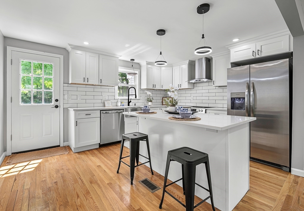 102 Hathaway Circle Arlington, MA 02476 - Photo 23 of 38 a kitchen with stainless steel appliances a dining table chairs refrigerator and cabinets