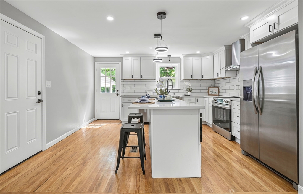 102 Hathaway Circle Arlington, MA 02476 - Photo 31 of 38 a kitchen with stainless steel appliances a refrigerator a sink dishwasher a stove and white cabinets with wooden floor