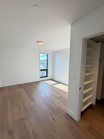 a view of an empty room with a window and wooden floor