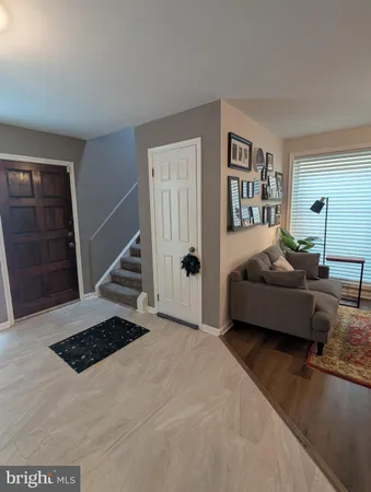 a living room with stainless steel appliances furniture wooden floor and a kitchen view