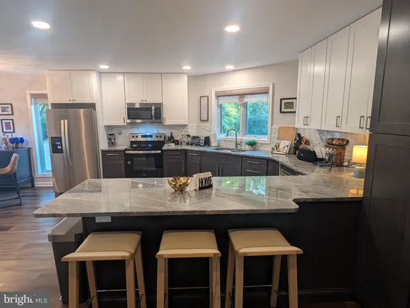 a kitchen with stainless steel appliances granite countertop a sink stove refrigerator and cabinets