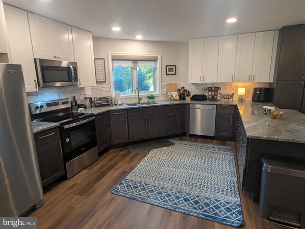 a kitchen with stainless steel appliances granite countertop a sink a stove a refrigerator cabinets and wooden floor