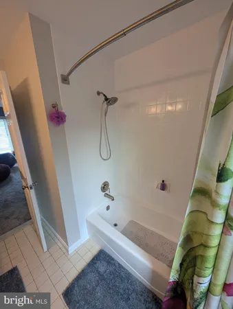 a bed sitting in a bedroom next to a window with a computer on a table and a bookshelf