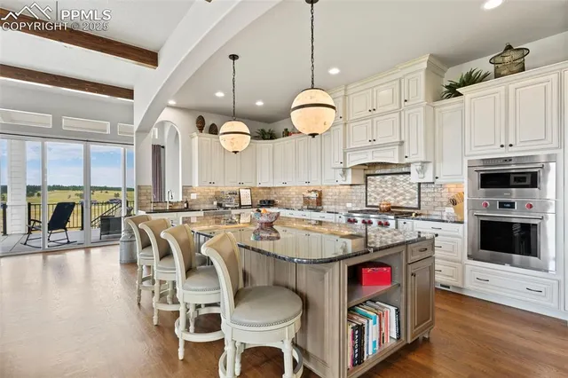 a kitchen with cabinets a stove a sink and a dining table with chandelier