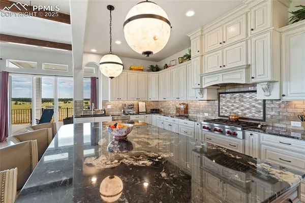 a large kitchen with stainless steel appliances granite countertop a stove a sink and a granite counter tops with white cabinets