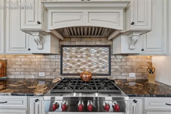 a kitchen with stainless steel appliances granite countertop white cabinets and a stove top oven