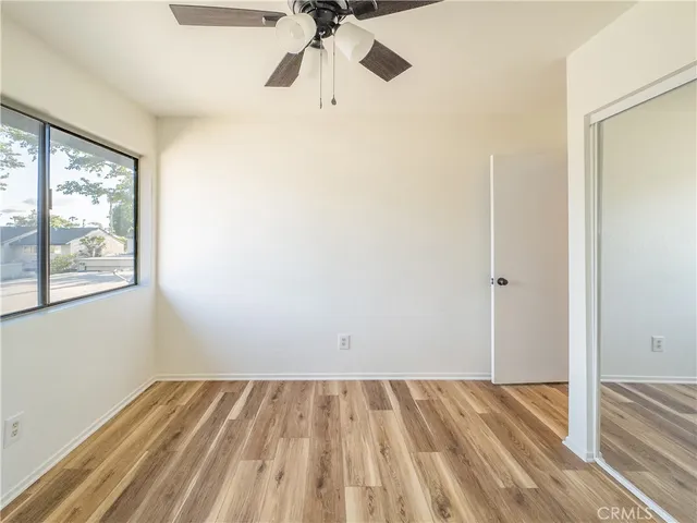 a view of empty room with wooden floor and fan