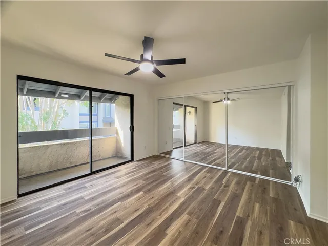 a view of empty room with wooden floor and fan