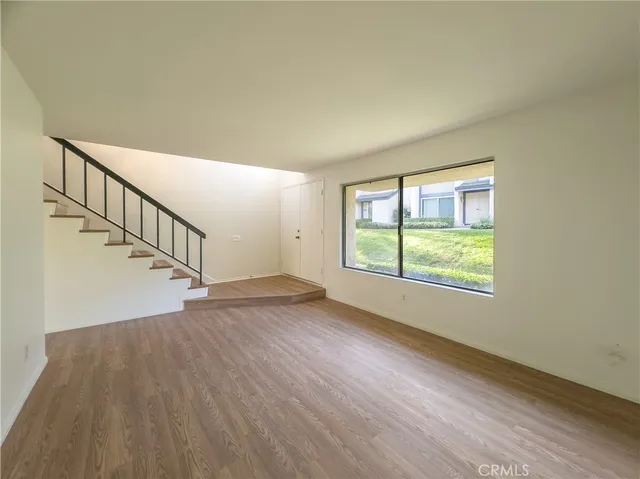 a view of an empty room with wooden floor and fan