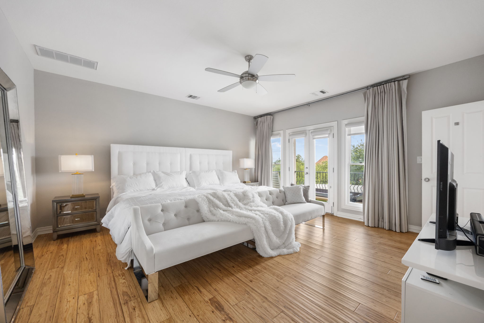 1910 Rue De St Tropez, Unit 6 Austin, TX 78746 - Photo 23 of 37 An airy primary bedroom suite features hardwood flooring and French doors opening to a private balcony.
