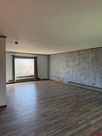 a view of an empty room with window and wooden floor