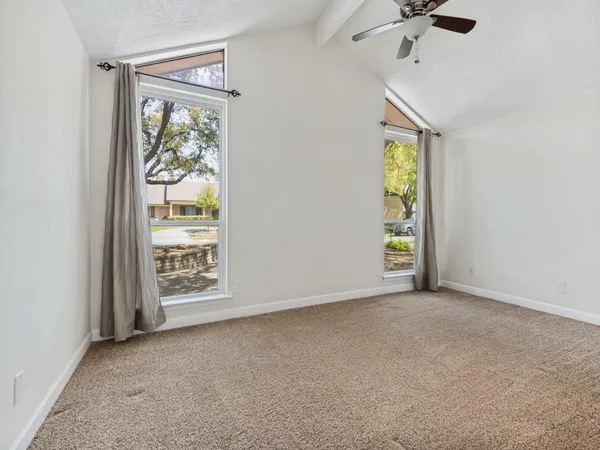 an empty room with wooden floor fan and windows