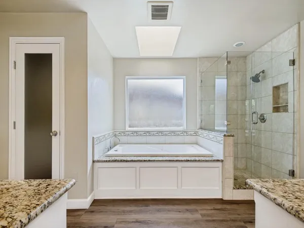 a spacious bathroom with a granite countertop tub sink shower and mirror