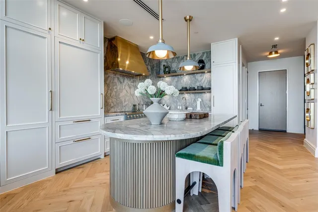 a kitchen with kitchen island stainless steel appliances a dining table chairs sink and cabinets
