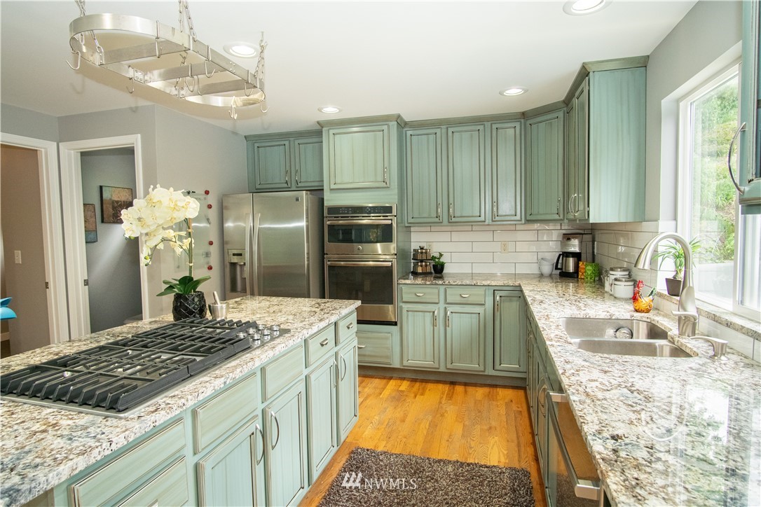 7215 South Rustic Road Seattle, WA 98178 - Photo 16 of 32 a kitchen with kitchen island granite countertop a stove a sink a refrigerator and a wooden cabinets