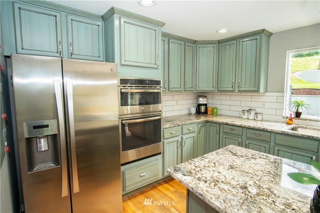 7215 South Rustic Road Seattle, WA 98178 - Photo 17 of 32 a kitchen with stainless steel appliances kitchen island granite countertop a refrigerator sink and cabinets