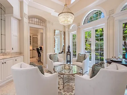 a living room with furniture chandelier and large windows