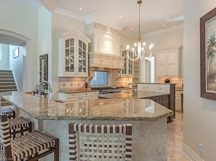 a kitchen with kitchen island granite countertop a stove and a chandelier